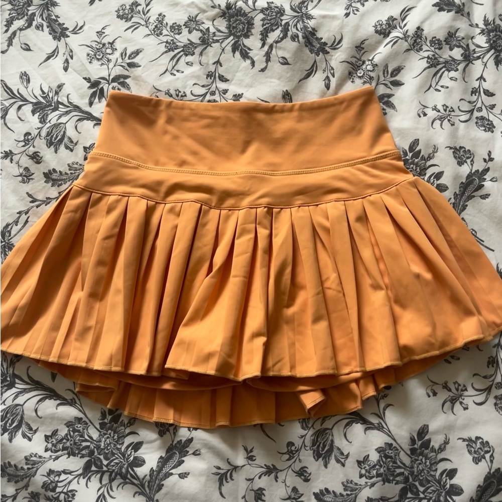 orange pleated tennis skirt